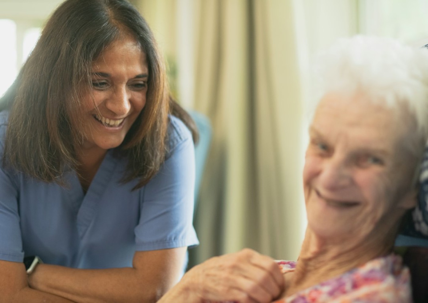 A home health aide sharing a laugh with an older woman